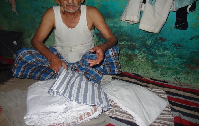 An elderly man folding garments for sale